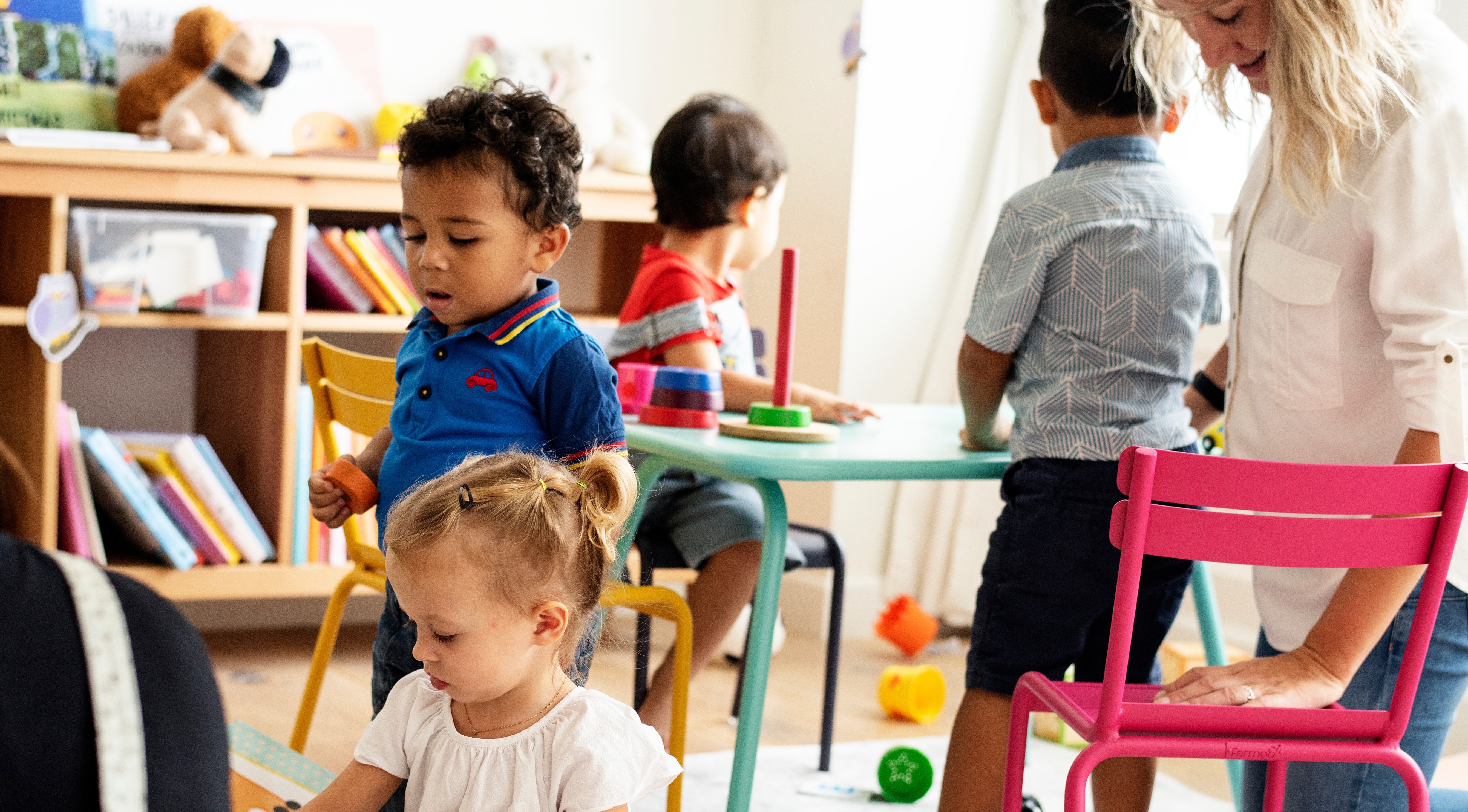 Nursery children playing with teacher in the classroom